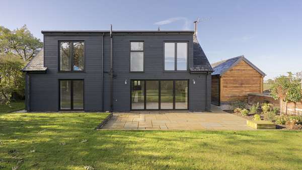External view of the rear of the property showing all aluminium windows and doors in black.