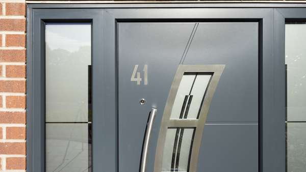 Close up of the stainless steel number and inset details on the grey aluminium front door.
