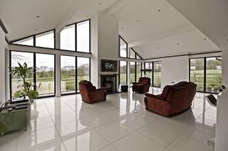Internal view of modern open plan living space flooded with natural light from large aluminium glazing installation.