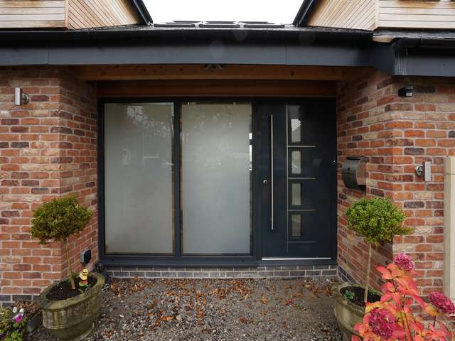 Aluminium entrance door with feature stainless steel handler and multipoint locking in RAL 7016.