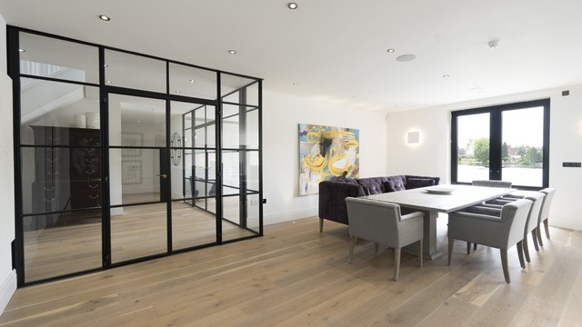 The dining area of this contemporary home showing the Crittall door and the lake through the aluminium french doors.