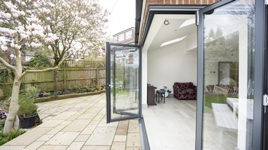 External shot of the RAL7016 aluminium bifolding doors showing the track and doors with the doors in an open position. The unique corner bifolding doors add the wow factor to any space with the floating corner of the building. Supplied and installed in Liverpool.