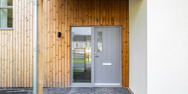 Grey entrance door with wood cladding surround.