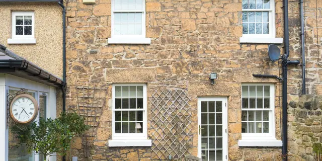 Close up of external view featuring new timber sash windows and single glazed door.