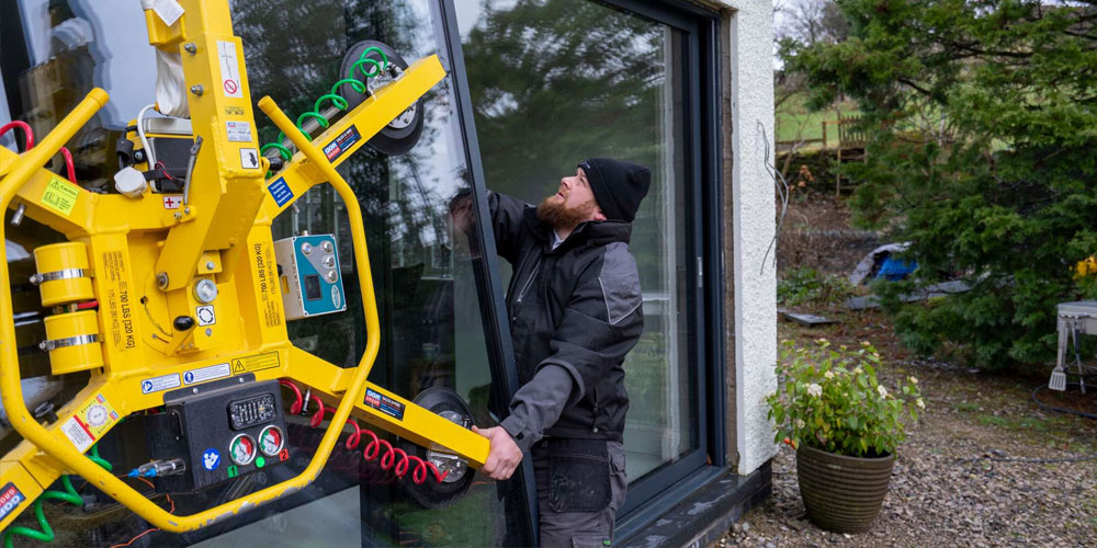 Fitters installing sliding door leaf utilising glass crane.