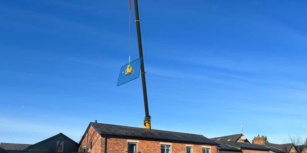 Wide shot of a crane arm lifting glass over property