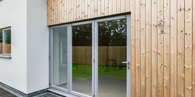 Closed bi-fold doors leading to garden with wood cladding surround