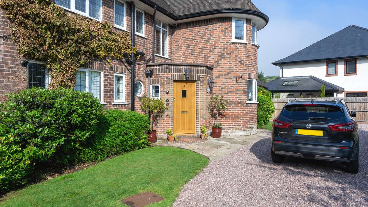 Oak entrance door leading to stone driveway.