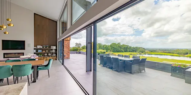 From the inside looking through the large sliding doors into the garden terrace with dining table in view