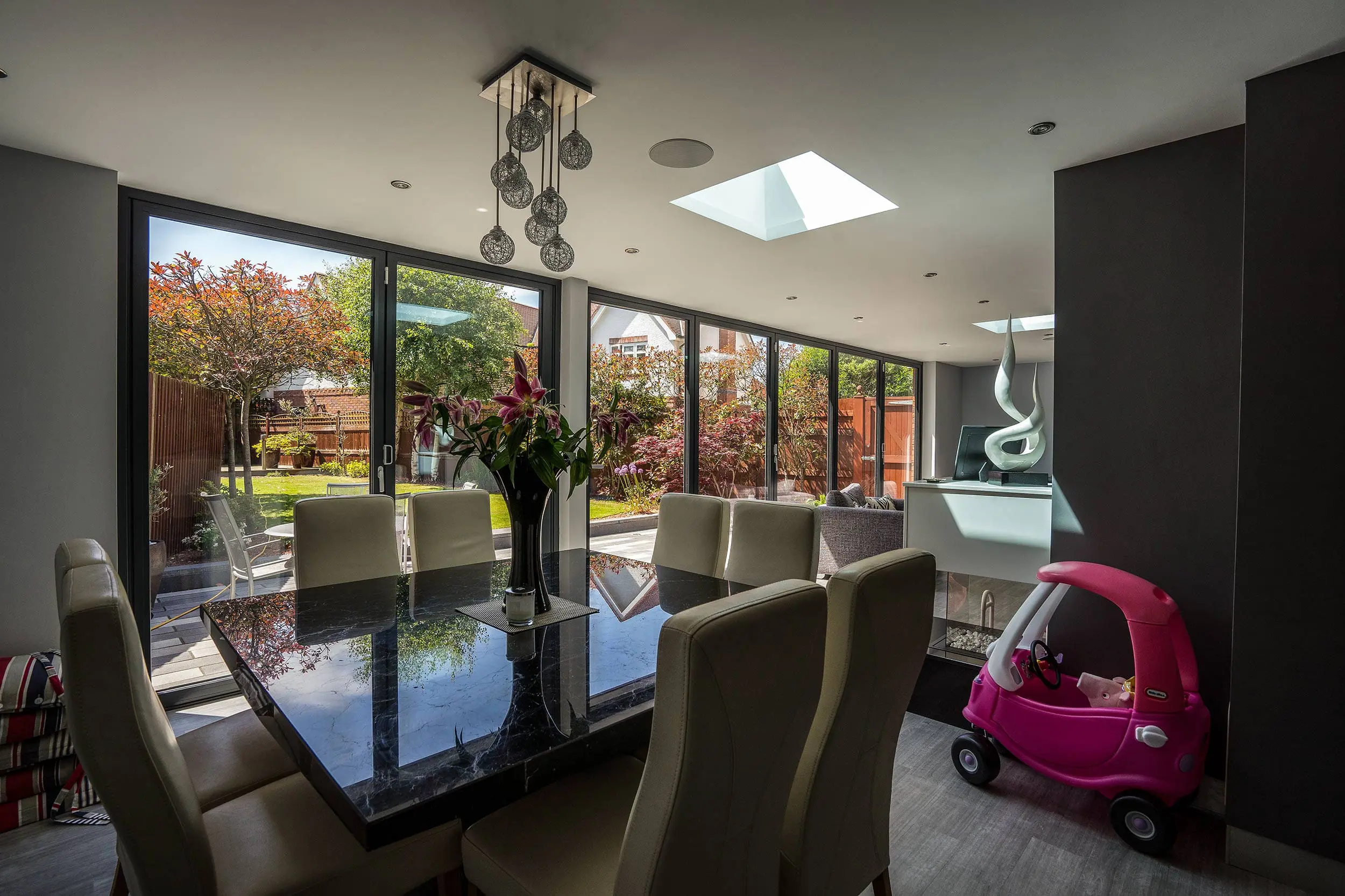 Internal dining area looking out onto the rear garden through aluminium bifold doors in Grey RAL 5016. Light is also brought into the space via two small roof lights.