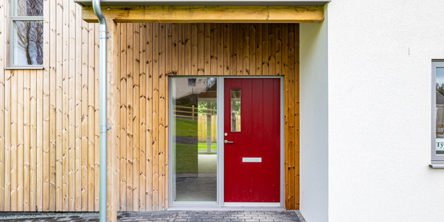 Red front door with wood cladding surround