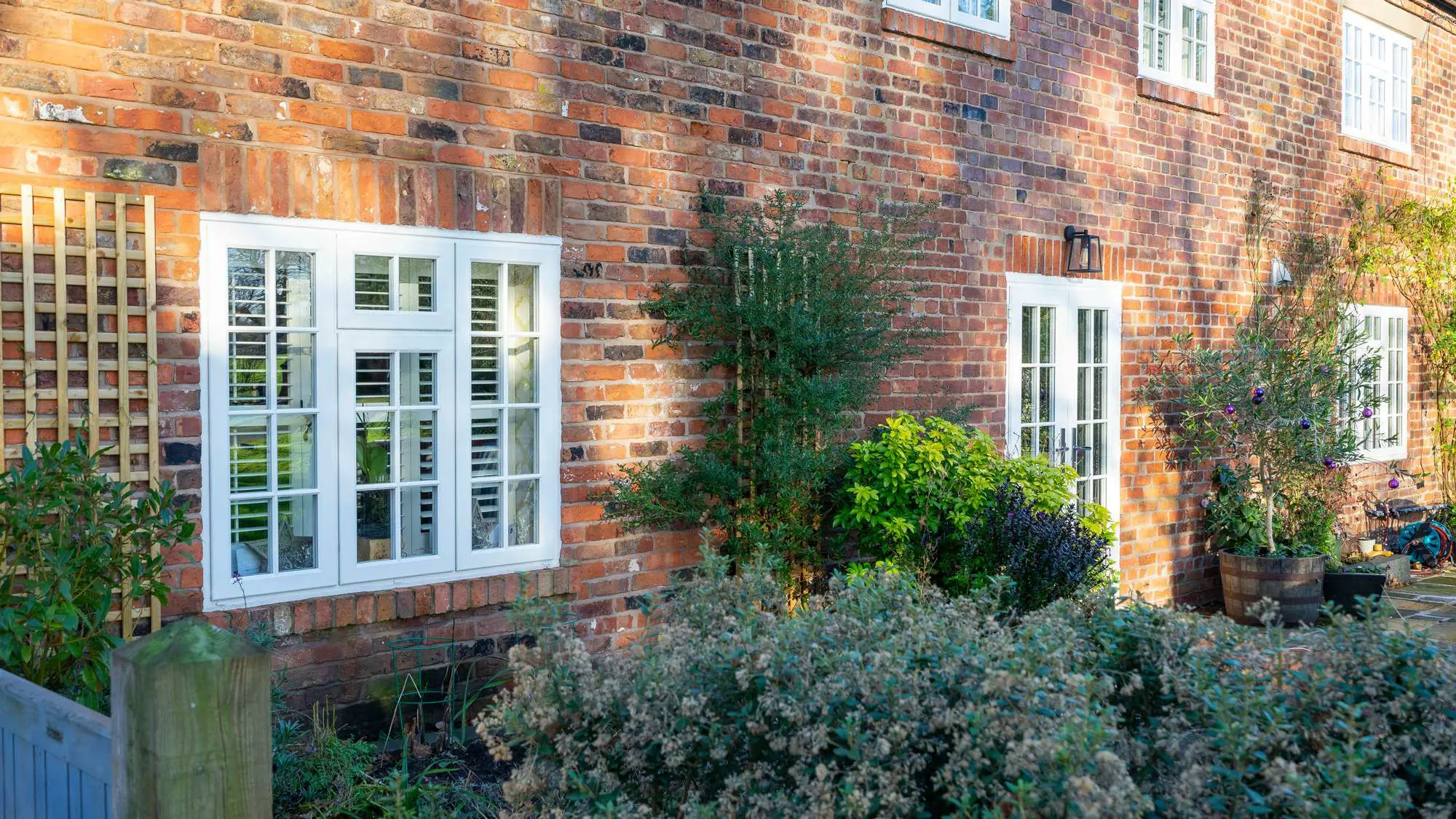 Timber alternative storm-proof windows in white contrasting against the red brickwork.