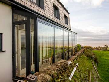 External shot of grey aluminium glass room.