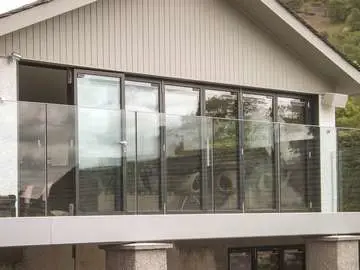 Large Aluminium bifold doors in RAL 7016 grey fitted with integrated blinds. The doors are made up of 7 individual panels create a large opening onto the customers balcony with feature glass balustrade.