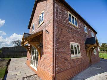 Corner shot of new build showing front and side of property with traditional styles UPVC, timber alternative windows and doors.