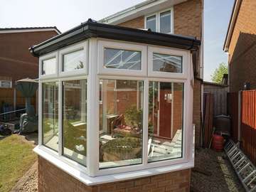 Replacement conservatory featuring a two tone colour scheme black roof with white windows giving a modern look. All glass is double glazed with a warm edge spacer for enhanced energy efficiency.