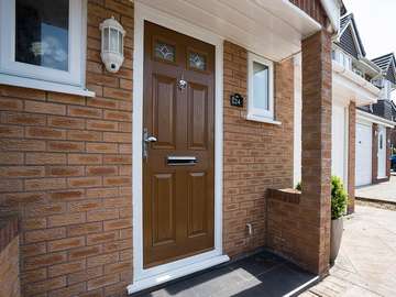 Brown wood effect composite entrance door installed in Great Sutton, Ellesmere Port. The door features lead light glazing, chrome door furniture and a white UPVC frame.