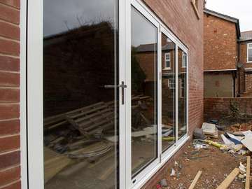 Close up of aluminium centor bifold doors in white aluminium. Four panel door with stainless steel feature handles and hinges.