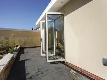 Close up shot showing triple panel white aluminium be-fold doors from Centor, installed in Wirral as part of the orangery build.