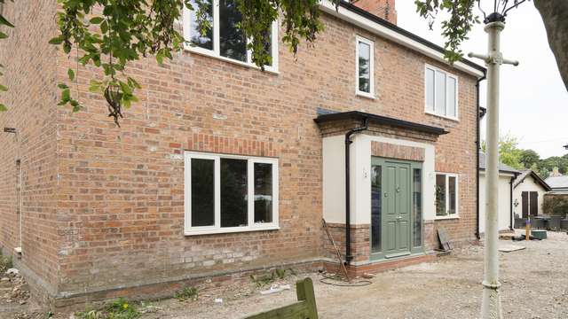 Full house installation of timber windows finished in cream with contrasting timber entrance door.