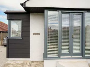 Close up of Rationel french doors with side lights and feature black clad property extension with stunning corner windows to maximise on the sea view.