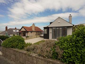 View from the street of property renovation in Rhosneigr, Anglesey showing Rationel alu-clad timber French doors with side lights in grey.