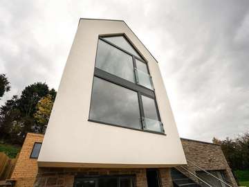 Feature double height aluminium windows with juliet balcony, top window follows the pitch of the roof and internal ceillings.