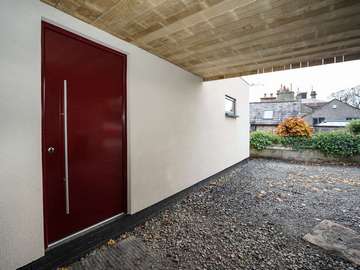 Aluminium entrance door finished in powder coated burgundy and stainless steel hardware for a modern look.