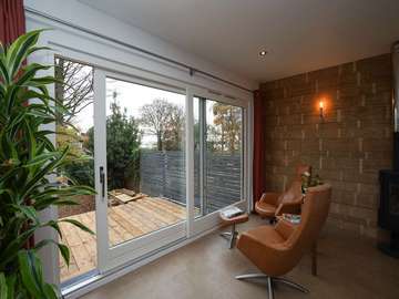 Internal view of white wooden slider with aluminium capping externally. Slider features floor to ceiling glass and stainless steel hardware and handles.