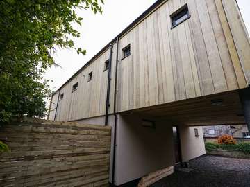 Rear view of full house Rationel installation of Alu-clad windows in grey on white and burgundy aluminium entrance door. As seen on Grand Designs.