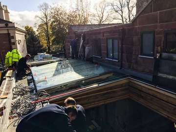 Installation of a large flat roof lantern constructed from glass with glass support for maximum light transfer.