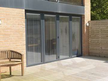 Close up photo showing internally fitted vertical blinds manually or electrically operated Example of aluminium triple glazed bi-fold doors. Aluminium bi-fold doors near Macclesfield SK11. Alumnus doors with 44mm triple glazing near Alderly Edge SK9. Aluminium Bi-fold doors near Wirral CH48 CH60. Alumnus Bi-fold doors triple glazed Liverpool Formby L37 near South Port PR8 Bi-fold doors near Crosby L23