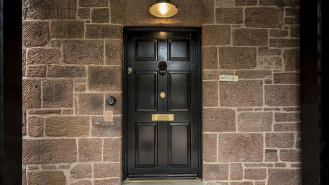 Full image of the timber entrance door contrasting perfectly with the original sandstone of the building which has been dressed perfectly.