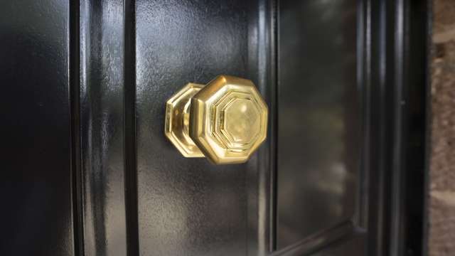 Close up of the brass door pull contrasting well against the black timber door.