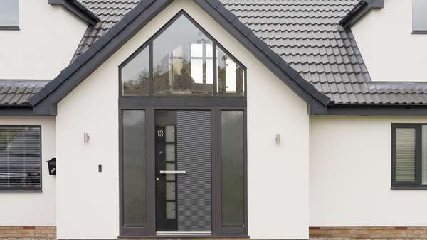 Aluminium Spitfire entrance door with sidelights and pitched top light in antracite grey with stainless steel handle.