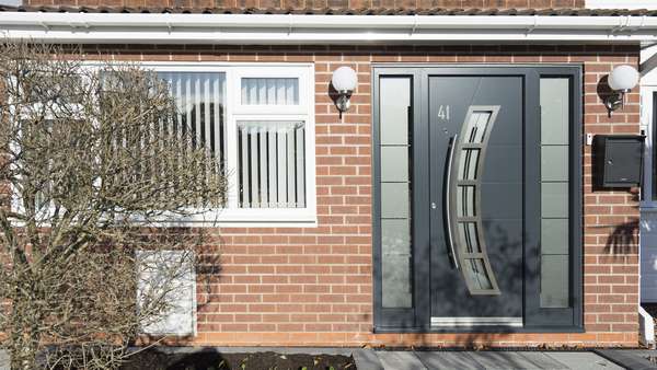 Straight on picture of the aluminium entrance door in anthracite grey with stainless steel accents and privacy glass.