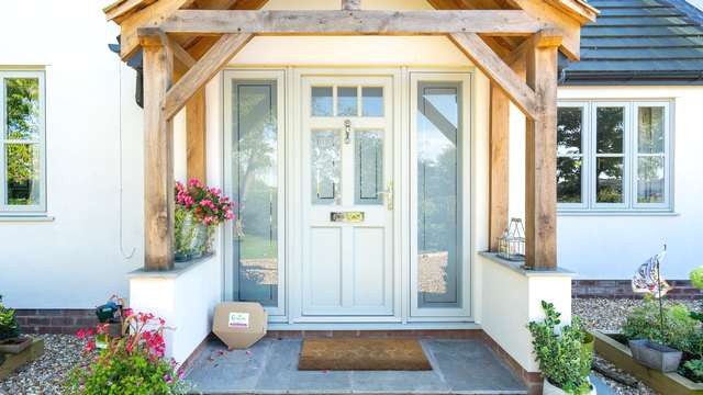 Timber alternative UPVC entrance door with chrome hardware and sidelights.