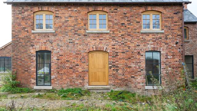 Front view showing a single arched Crittall door and windows.