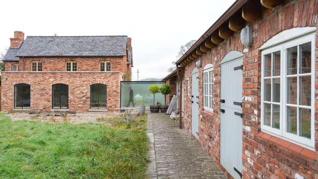 Wide view of the rear of the property showing crittall arched windows and doors and the glass corridor.