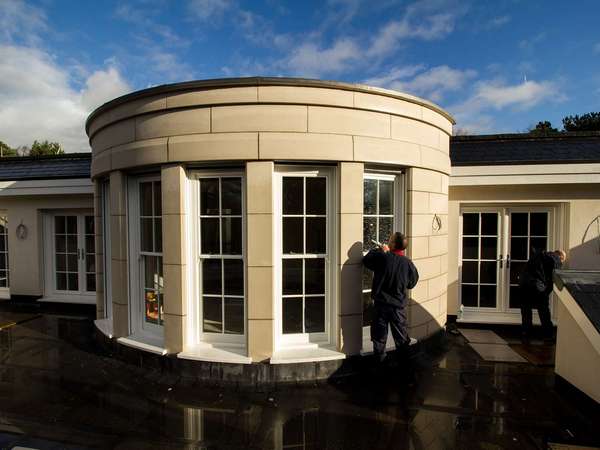 External shot of our installers adding the finishing touches to several large sash windows to complete this rounded bay.