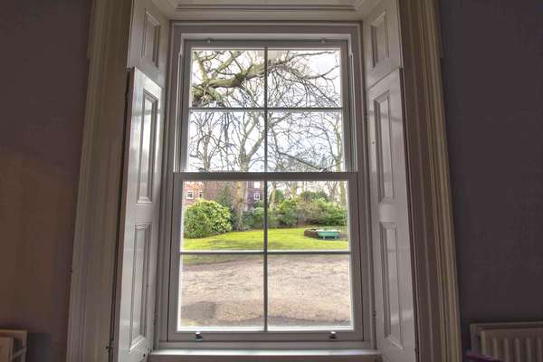 Internal shot of UPVC sash window with original woodern shutters.