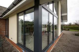 Extrernal view of large aluminium window installation in Ormskirk, Liverpool. Large windows and doors allow a large amount of light to enter this stunning open plan living area in Liverpool. Although large amounts of glass have been installed the use of triple glazing and thermally broken frames ensure this is a warm space useable year round. This picture highlights the aluminium pressings used on the corner to create a modern seamless look to this extension.