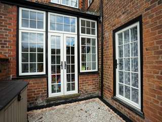 Traditional french doors with top and side lights with cast iron door hardware to match that of the original windows and doors.