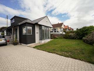 Corner view of detached bungalow renovation in Anglsey featuring Aluminium clad timber windows and doors with feature corner window and entrnace door.