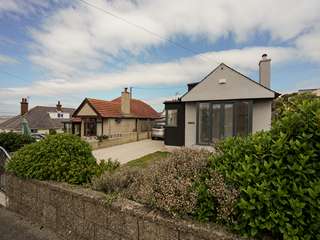 View from the street of property renovation in Rhosneigr, Anglesey showing Rationel alu-clad timber French doors with side lights in grey.