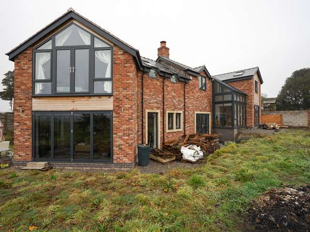 Rear of property showing bifold doors, and multiple sets of french doors as well as feature glass room.