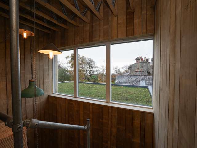 Large internal window looking out onto the green roof of the new living room.