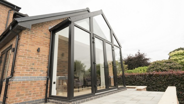 Close up image of the glass room added to the living room within this home.