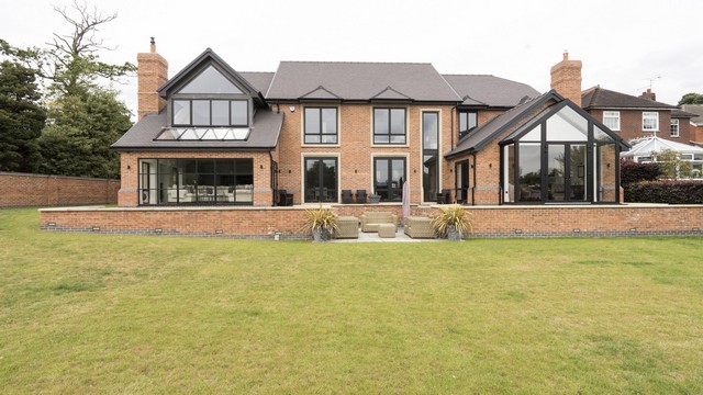 Full view of the rear of the house, showing the complete glazing solutions, a blend of both black powder coated steel and aluminium.