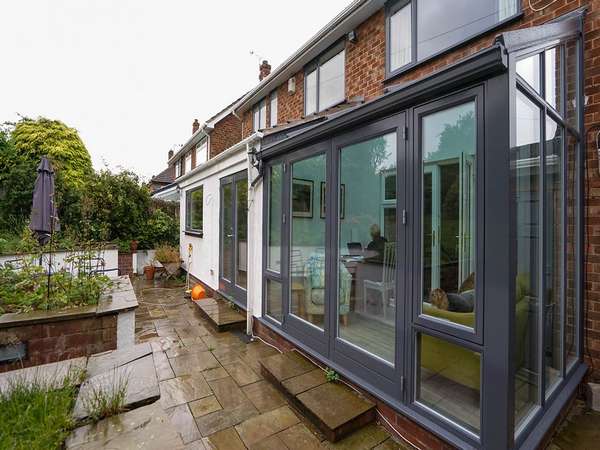 Overview of the rear of the property showing garden room and window details.